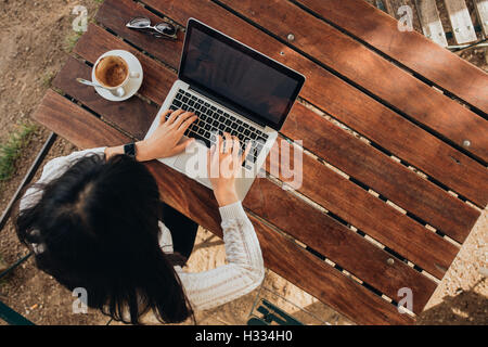 Draufsicht der jungen weiblichen arbeiten auf ihrem Laptop in einem Café. Ansicht von oben geschossen Frau sitzt an einem Tisch mit einer Tasse Kaffee b Stockfoto