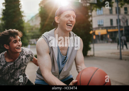 Zwei junge Freunde, Basketball zu spielen und Spaß haben. Streetball Spieler mit einem Spiel der Basketball auf Platz im Freien. Stockfoto