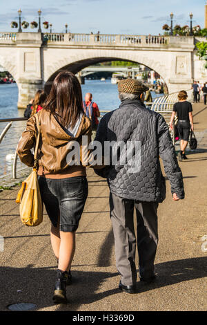 Eine junge Frau geht mit ihrem Vater in der Nähe der Themse in Kingston-Upon-Thames in Surrey, England, UK Stockfoto