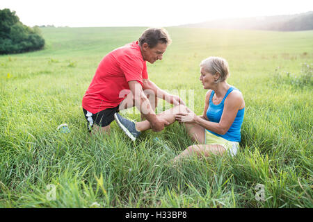 Senior-Läufer im grünen Bereich. Frau mit Knie verletzt. Stockfoto