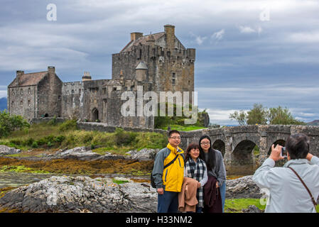 Asiatische Touristen posieren vor Eilean Donan Castle im Loch Duich, Ross und Cromarty, Western Highlands von Schottland, Großbritannien Stockfoto