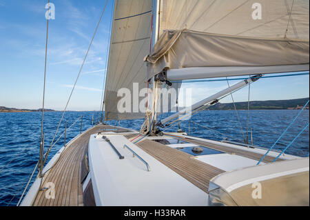 Segelboot Teak Deck und Segel gehisst, Blick aus dem Cockpit auf den Bogen. Stockfoto