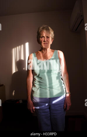 Portrait einer älteren Frau, die im Schatten eines Fensters blind Stockfoto