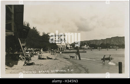 Waikiki-Strand-Szene mit Sonnenanbeter, Surfer und hölzernen Surfboards in Honolulu, Hawaii-Territorium c1920s. Stockfoto