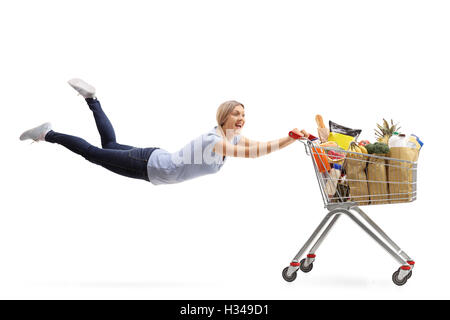 Glückliche Frau, gezogen von einem Einkaufswagen voller Lebensmittel isoliert auf weißem Hintergrund Stockfoto