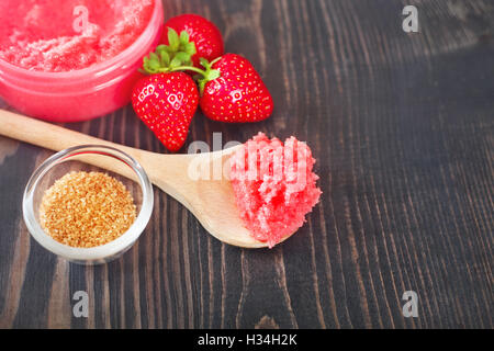 Erdbeer-Körperpeeling mit braunem Zucker auf dem hölzernen Hintergrund Stockfoto