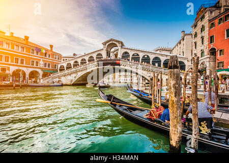 Klassische Ansicht der traditionellen Gondeln am berühmten Canal Grande mit der berühmten Rialto-Brücke bei Sonnenuntergang in Venedig, Italien Stockfoto
