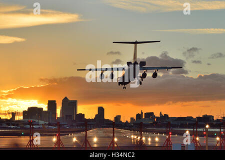 Ein Schweizer RJ100 hereinkommt, wenn die Sonne untergeht am London City Airport zu landen. Stockfoto