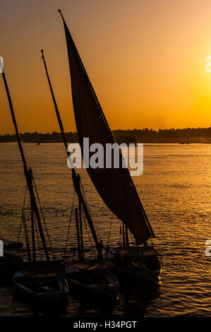 Luxor, Ägypten. Die Sonne geht über dem Nil. Feluken am Ostufer. Stockfoto