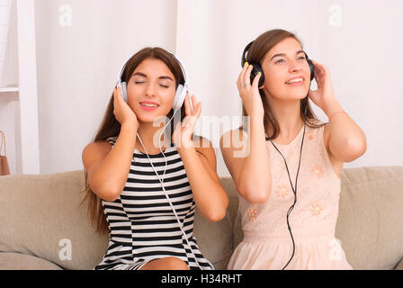 Freunde hören Musik im Kopfhörer sitzt auf dem Sofa im Zimmer Stockfoto