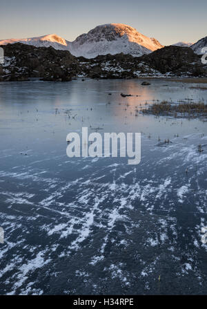 Abenddämmerung Sonnenlicht am großen Giebel über einen gefrorenen Innominate Tarn, Heuhaufen, englischen Lake District Nationalpark Stockfoto