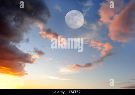 Wolken Mond ist eine lebendige, bunte Wolkengebilde bei Sonnenuntergang mit einem ätherischen Vollmond steigt in den Himmel. Stockfoto