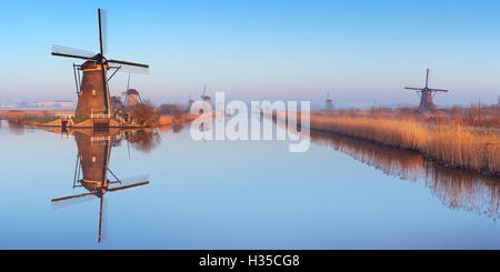 Traditionelle holländische Windmühlen spiegelt sich in perfekt stilles Wasser an einem kalten Morgen im Winter, bei Kinderdijk in den Niederlanden Stockfoto