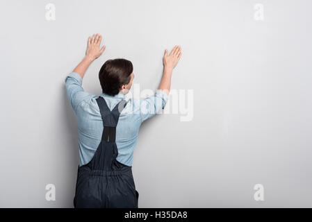 Starke gut aussehender Mann berühren die Wand Stockfoto