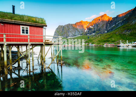 Typisches Haus der Fischer namens Rorbu beleuchtet von Mitternachtssonne, Reine, Nordland Grafschaft, Lofoten-Inseln, Arktis, Norwegen Stockfoto