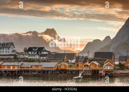 Sonnenuntergang auf dem Fischerdorf umrahmt von felsigen Gipfeln und Meer, Sakrisoya, Nordland Grafschaft, Lofoten-Inseln, Arktis, Norwegen Stockfoto