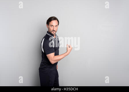 Angenehme, gut aussehender Mann zeigt seine Stärke. Stockfoto