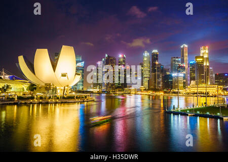 Der Lotus Blume geformt ArtScience Museum mit Blick auf Marina Bay mit der Skyline der Stadt darüber hinaus in der Nacht, Singapur beleuchtet Stockfoto