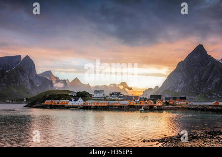 Sonnenuntergang auf dem Fischerdorf umrahmt von felsigen Gipfeln und Meer, Sakrisoya, Nordland Grafschaft, Lofoten-Inseln, Arktis, Norwegen Europa Stockfoto