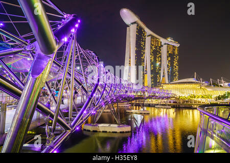 Menschen, die ein Spaziergang auf der Helix-Brücke in Richtung Marina Bay Sands und ArtScience Museum bei Nacht, Marina Bay, Singapur Stockfoto