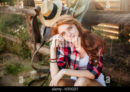 Attraktive rothaarige junge Frau Cowgirl sitzen und entspannen im freien Stockfoto