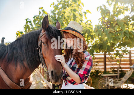 Glücklich zärtliche junge Frau Cowgirl Hut Ruf mit ihrem Pferd auf der ranch Stockfoto