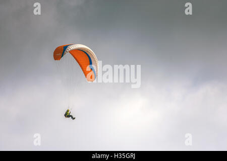 Solo-orange Gleitschirmspringen, Paragleiter, Hanglider fliegen, gegen grauen grauen Himmel Stockfoto