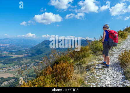 Weibliche Walker mit roten Rucksack über Orpierre, Savoie, Frankreich, blauer Himmel und Sommer Stockfoto