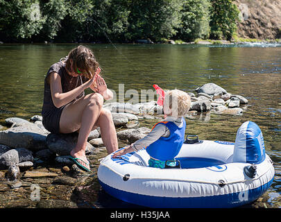 Ein Kind seiner Mutter mit einer Wasserpistole schießen. Stockfoto