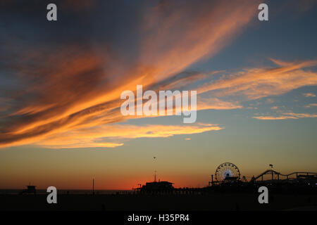 Dramatischen Sonnenuntergang am Strand von Santa Monica Pier, Riesenrad und Achterbahn im Hintergrund. Stockfoto