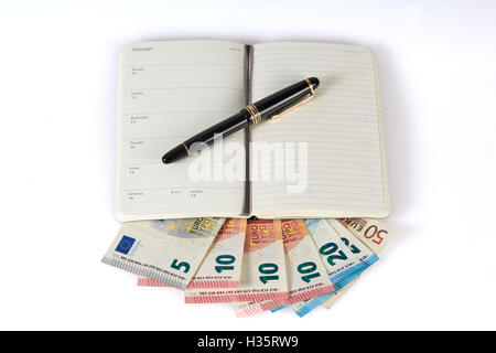 Geld verdienen mit dem Schreiben auf Geld Banknoten symbolisierten mit Stift und Notizbuch Stockfoto