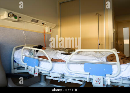 Abendlicht in Zimmer, Frau, im Krankenhausbett liegen. Stockfoto