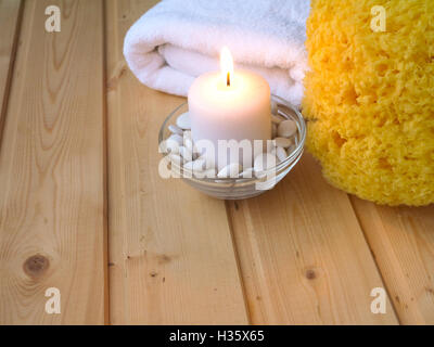 Handtuch, brennende Kerze und Schwamm auf dem hölzernen Hintergrund Stockfoto