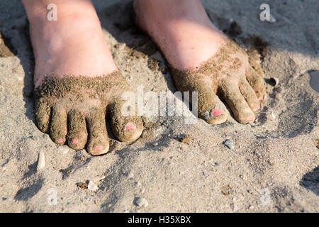 Füße mit rosa lackierten Fußnägel bedeckt im Sand am Strand. Stockfoto