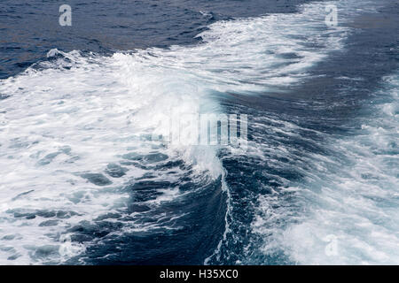 Wildwasser-Churing in einem tiefblauen Meer hinter einem rasenden Boot durch seine Propellern im Wasser verursacht. Stockfoto