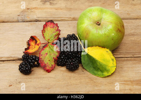 Brombeeren und Kochapfel mit Herbst Blätter auf alte verwitterte Holz Stockfoto
