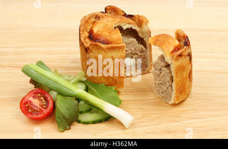 Handgemachte Warmwasser Kruste Pork Pie mit Salat auf ein Schneidbrett aus Holz Stockfoto