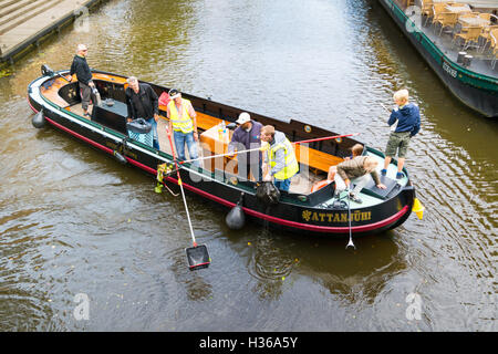 Menschen auf das Boot zu sammeln Links Abfall Reinigung Kanal Wasser aus Wurf in der Innenstadt von Leiden, Niederlande Stockfoto