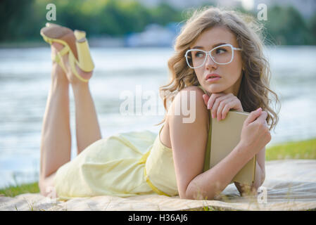 Romantisches Mädchen mit Buch im Citypark am Fluss-Ufer Stockfoto