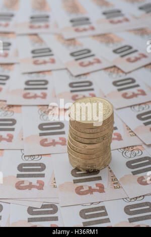 Aufgefächert altes Design £ 10 Banknoten mit Stapel alter Stil £ 1 Münzen - als visuelle Metapher für das Konzept der britischen Währung, Löhne, Wirtschaft und Inflation. Stockfoto