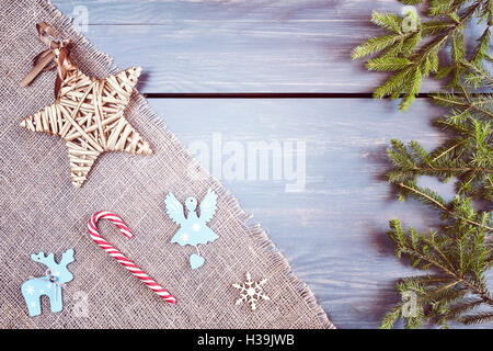 Retro stilisierte Weihnachten Hintergrund, Fichte Zweige mit Verzierungen auf einem rustikalen Holztisch, Ansicht von oben mit Textfreiraum. Stockfoto