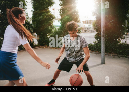 Zwei junge Mann und Frau am Basketballplatz mit Ball dribbeln. Freunde auf Court Basketball zu spielen und Spaß haben. Stockfoto