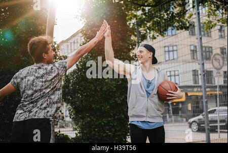 Zwei junge Freunde geben hohe fünf nach einem Spiel Streetball. Teenager Basketball-Spieler nach einem Spiel zu genießen. Stockfoto