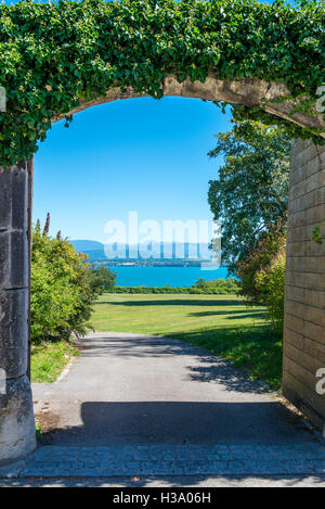 Blick auf den Genfer See durch ein offenes Tor in einer Steinmauer bedeckt mit Efeu, Nyon, Kanton Waadt, Schweiz Stockfoto