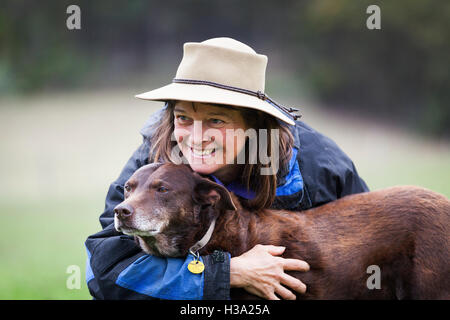 Eine lächelnde Bauer Frau umarmt ihren Hund. Stockfoto