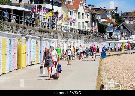 Reihe von bunten Strandhäuschen entlang der Kante des Strandes und der Promenade mit Touristen genießen die Einstellung, Lyme Regis, UK. Stockfoto