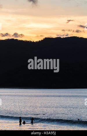 Ticos (lokale Wort verwendet, um native Costaricaner beschreiben) spielen im Wasser bei Sonnenuntergang an der Küste von Guanacaste. Stockfoto