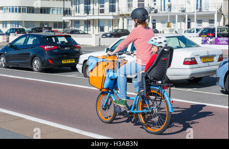 Frau und Kind auf einem Fahrrad mit Kindersitz auf einem Radweg Radfahren. Stockfoto