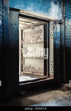 Abstrakte Dunkle grungy industrielle Interieur mit blauen rostigen Metallwand und offen schwere Stahltür Stockfoto