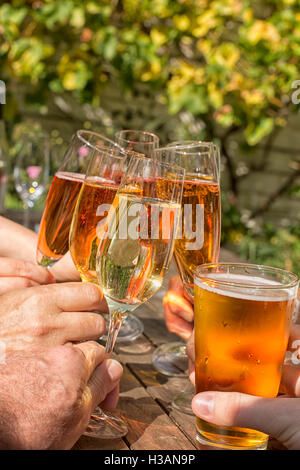 Gruppe von Freunden, die klirrende Gläser Champagner im Garten Stockfoto